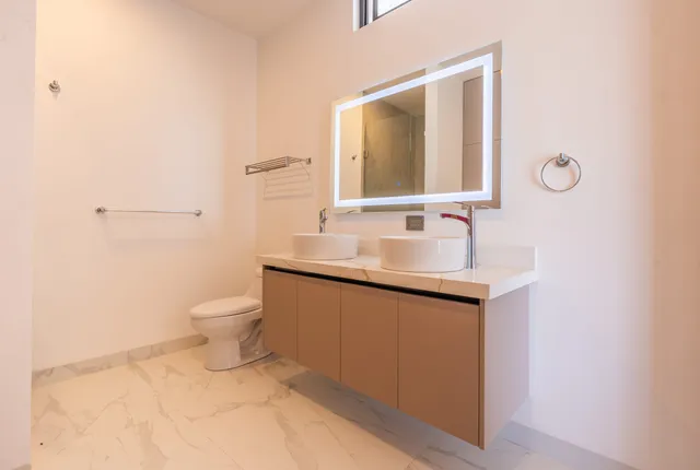Baño con doble lavabo tipo vessel y espejo LED