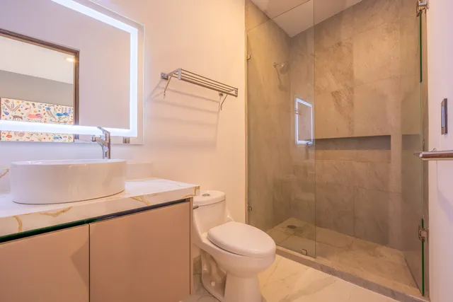 Baño con lavabo tipo vessel, espejo LED y regadera de cristal