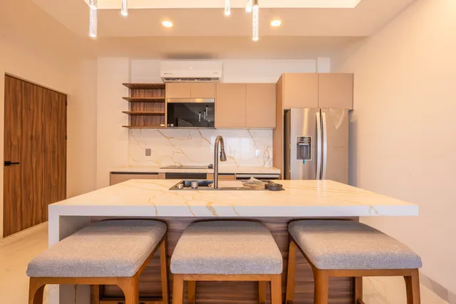 Isla de cocina con barra para tres personas en el departamento modelo de Vista Los Sueños