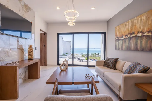 Sala con sofá y vista al mar desde la terraza en el departamento modelo de Vista Los Sueños