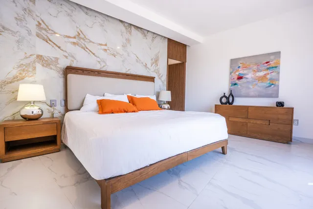 Recámara principal con pared de mármol y muebles de madera